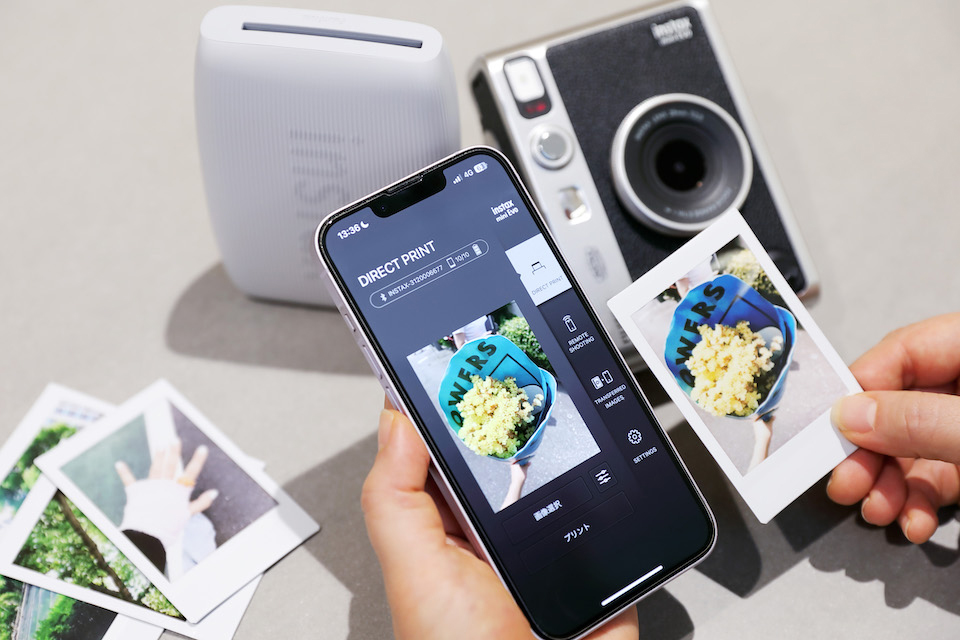 専用アプリを開いたスマホとチェキプリントを手に持っている写真