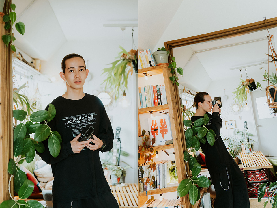観葉植物に囲まれた部屋で撮影しているOTAさんの写真