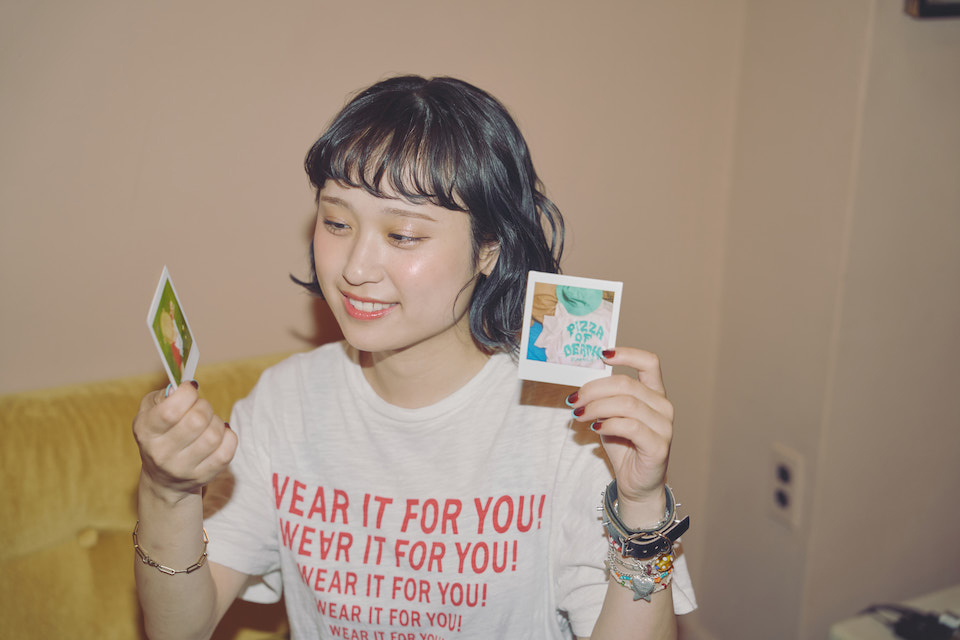 なちさんが両手に持ったチェキプリントを眺めている様子
