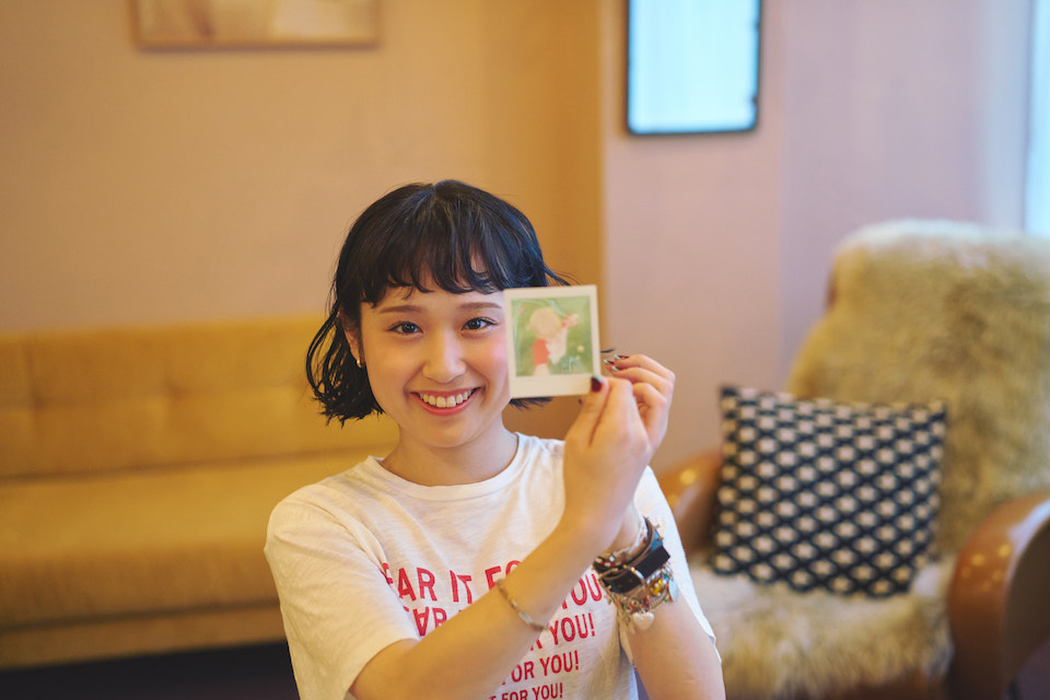 チェキプリントを手に持った笑顔のなちさんの写真