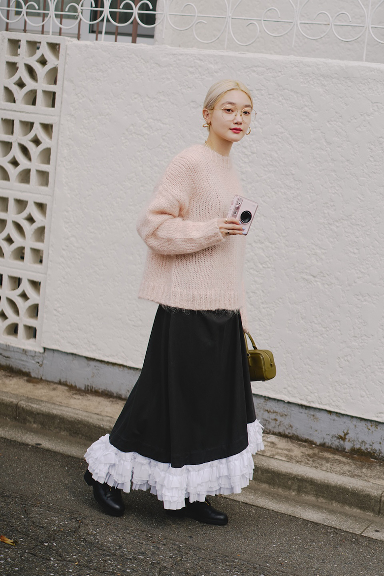 ピンクのニットに落ち着いた色のスカートを合わせたコーディネート