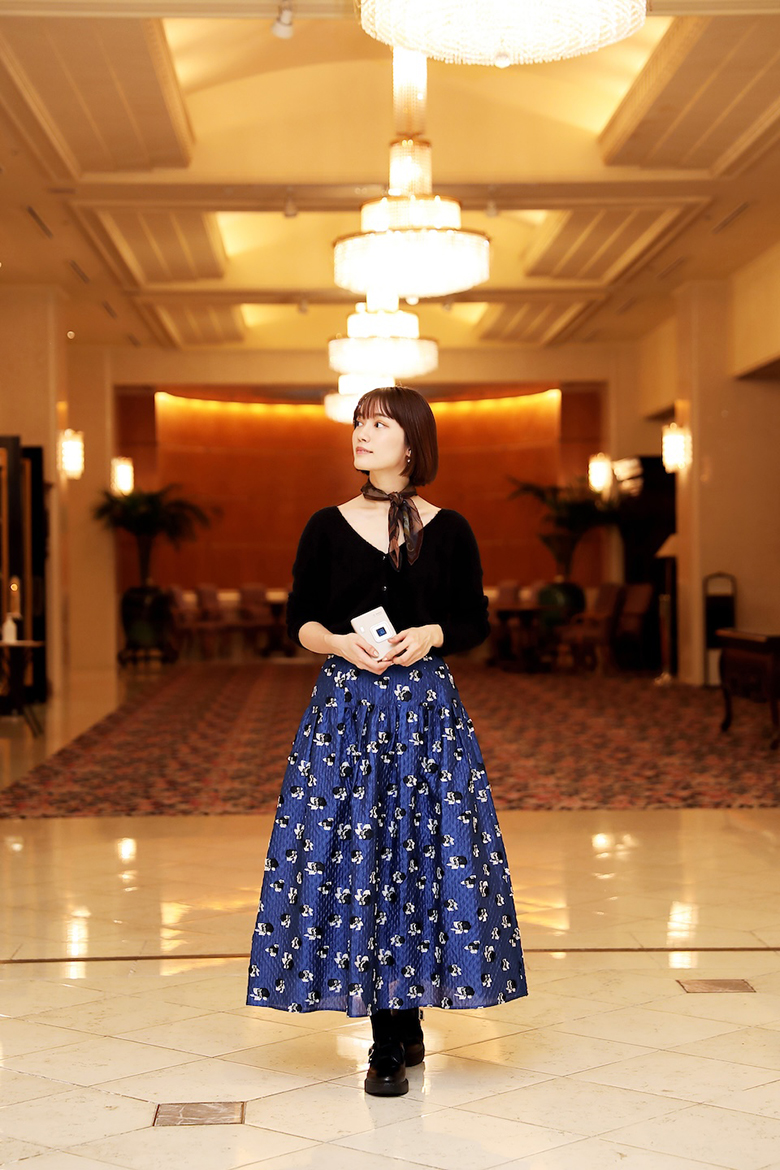 ホテル内でmini LiPlay+™を持って立っている甲斐さん