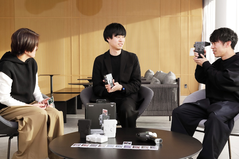 担当者3名が製品やチェキプリントを手に取っている写真