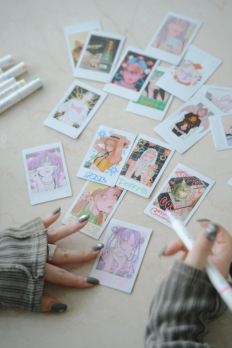 たくさん並べられたチェキプリントとNAKAKI PANTZさんの手元の写真