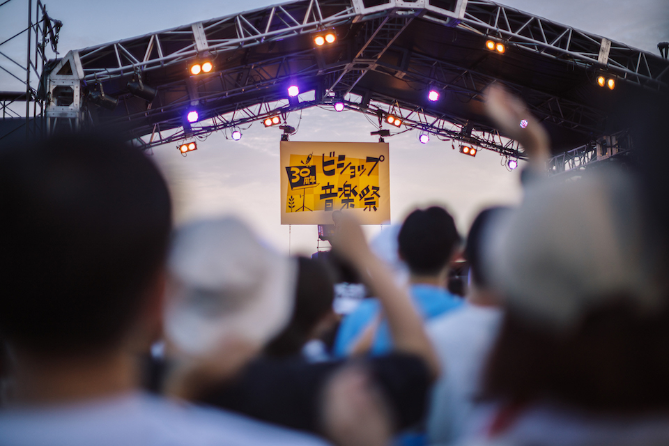 照明のついた音楽ステージと音楽を楽しんでいる来場者