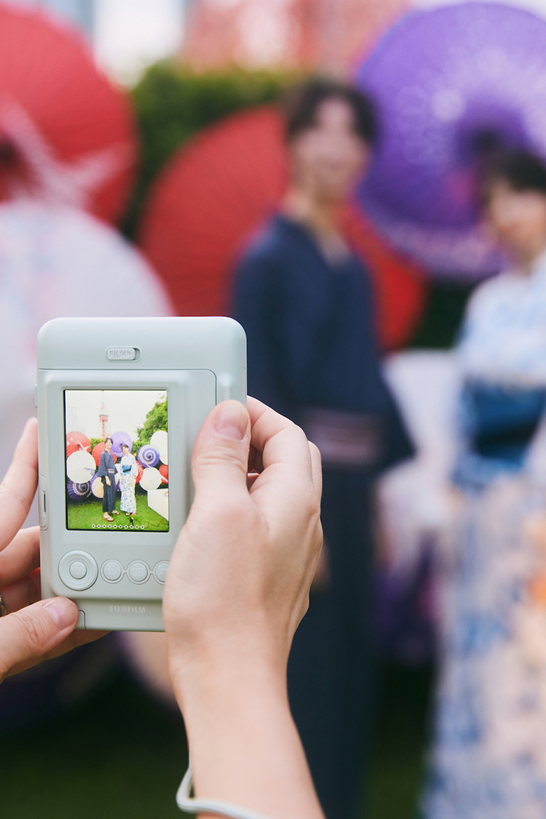 東京タワーを背景に、浴衣を着た男女をmini LiPlayで撮影している写真